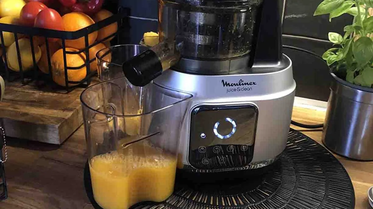 Extracteur de jus argenté versant un jus d'orange fraîchement pressé