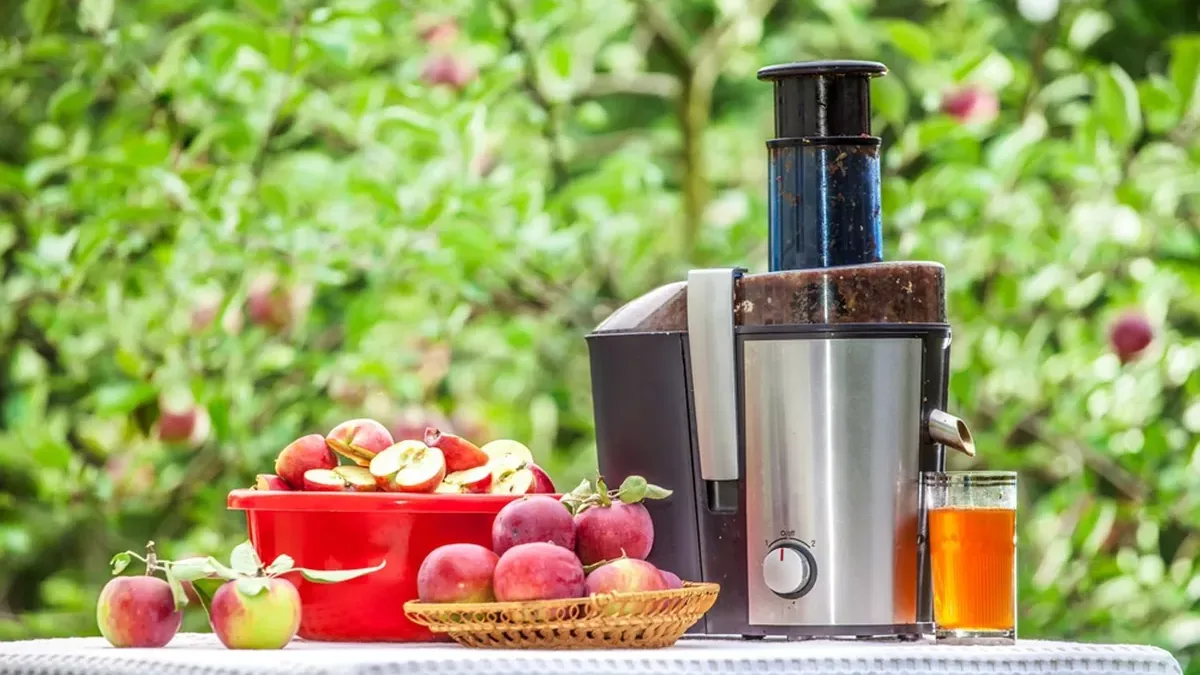 Extracteur de jus utilisé en extérieur avec des pommes fraîchement récoltées