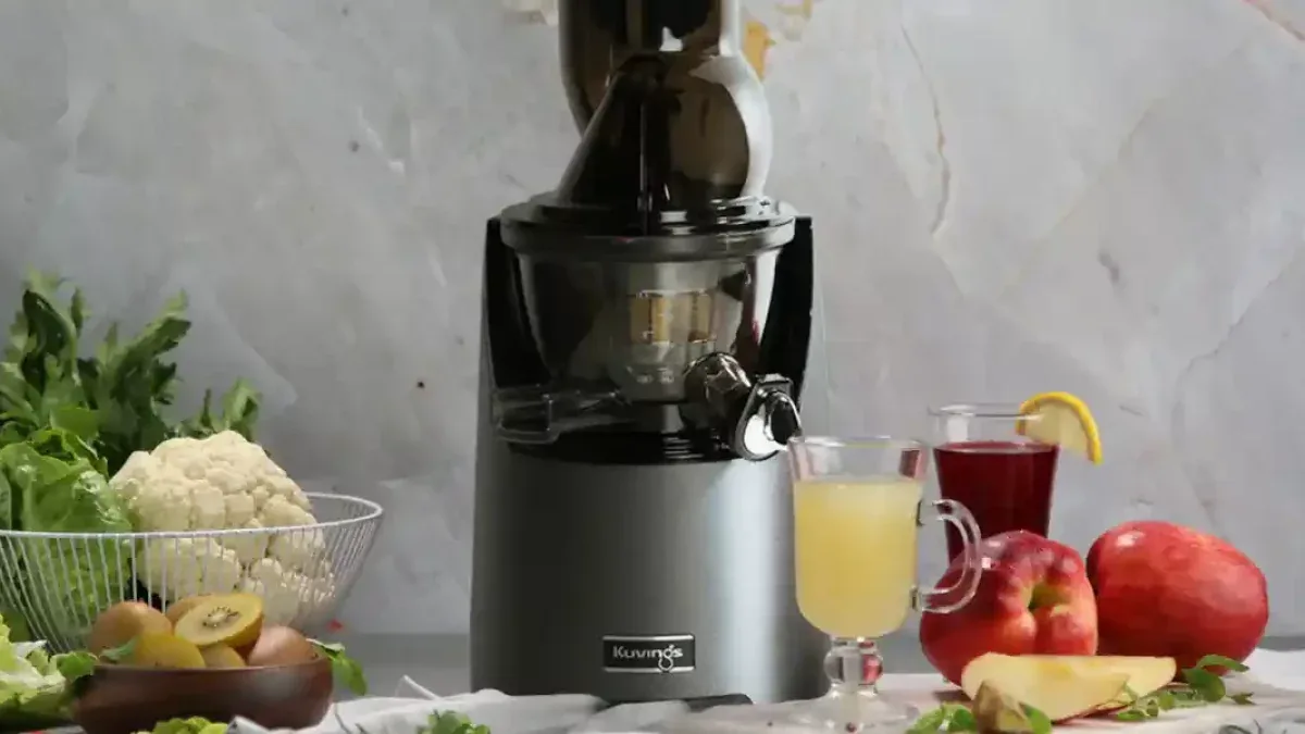 Extracteur de jus gris entoure de chou-fleur, kiwis et pommes prets a etre presses