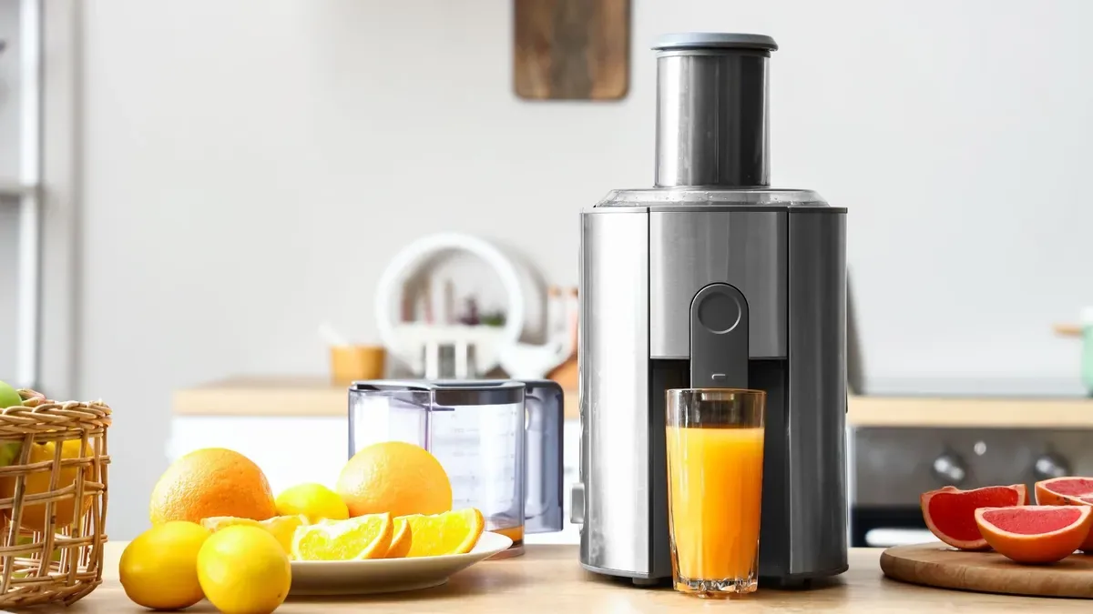 Extracteur de jus gris et silencieux avec oranges, citrons et pamplemousse a cote d'un verre de jus