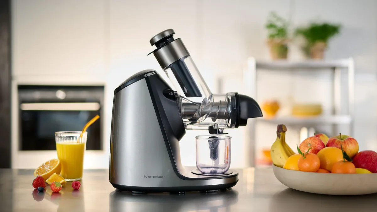 Extracteur de jus incline avec jus d'orange, baies fraiches et corbeille de fruits variee